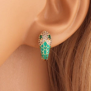 Macro shot of gold snake earring with green enamel and sparkling zircon details on model