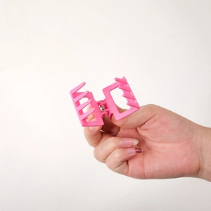 Matte pink square hair claw clip held by hand showing strong spring and teeth