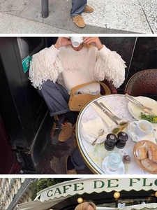 Detailed view of khaki handbag with silver metal eyelets and long white fringe sweater