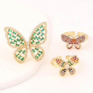 Adjustable gold butterfly rings set with colorful zircon stones on white background
