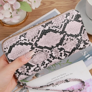 Pink snake print long zip wallet with wristlet strap on a stylish wooden desk
