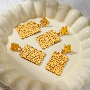 Vintage geometric woven gold titanium steel rectangle earrings on a wave tray