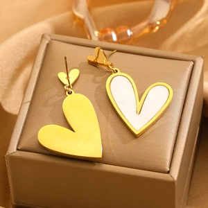 Asymmetric gold heart earrings with white mother of pearl inlay on jewelry box