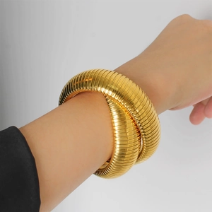 Macro shot of gold-plated snake-shaped coil bracelet with vintage ribbed metal texture