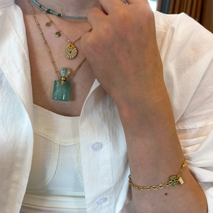 Detail of layered gold necklace with turquoise beads and perfume bottle pendant