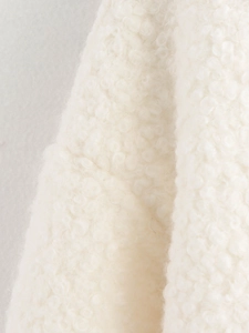 Close-up macro view of high-quality cream white faux shearling fabric texture