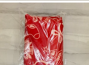 Detail of red Christmas tree skirt fabric with holiday patterns inside clear plastic packaging