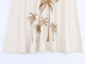 Nahaufnahme der Kokosnussbaum-Stickerei und Leinentextur auf beigem Sommerkleid