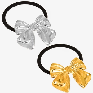 Detail view of stylish gold and silver metal bow pendants on black elastic hair ties