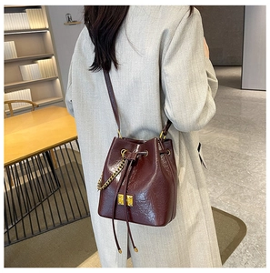 Dettaglio borsa a secchiello in pelle bordeaux con catena dorata e nappe eleganti