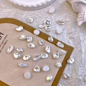 Macro shot of baroque style irregular pearl nail art charms on white textured paper
