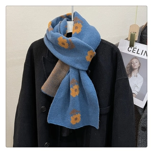 Detail of blue knit scarf with yellow flower jacquard texture on black wool coat