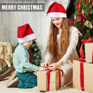Classic red plush Christmas hats for adults and kids shown in a warm holiday setting