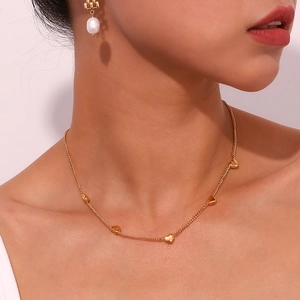 Detail of 18K gold plated necklace with heart pendants and pearl earring on model