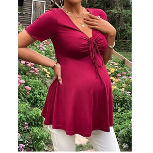 Close-up of wine red maternity dress featuring V-neck and drawstring detail in garden