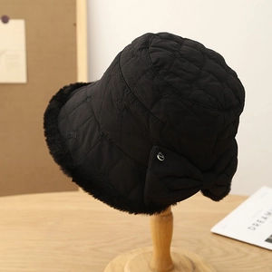 Detailed view of black quilted bucket hat featuring plush faux fur trim and a large bow detail