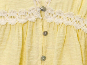 Close-up of yellow wrinkled fabric with crochet lace trim and pearl buttons