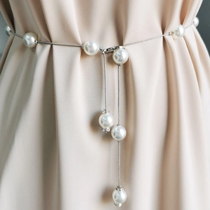 Close-up of elegant pearl waist chain with silver metal tassels on silk fabric