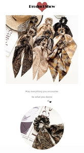 Detail of leopard and snake print hair scrunchies with long ribbons on a white surface