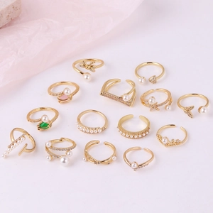 Flat lay of 14-piece gold bohemian ring set with pearls and zircons on pink background