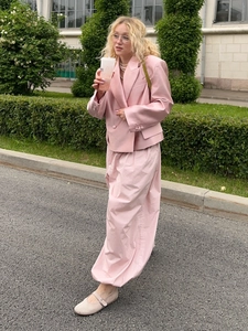 Detail shot of the cropped pink double-breasted blazer and draped harem-style skirt