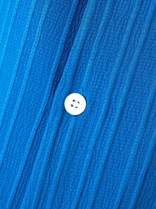 Macro detail of blue men's linen henley shirt showing striped texture and white button