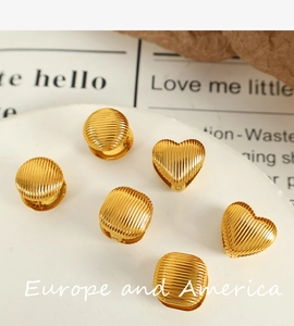 Gros plan de boucles d'oreilles dorées géométriques avec texture rayée sur plateau