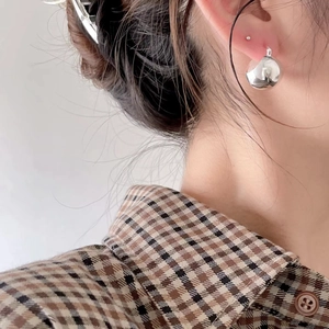 Close-up of minimalist silver ball stud earring on earlobe with a polished metal finish