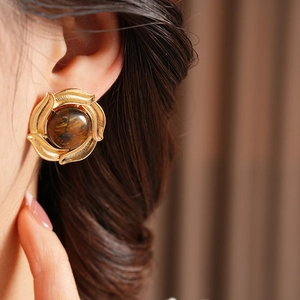 Close-up of retro golden leaf texture earrings with brown tiger eye stone on model