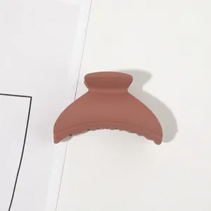 Detail of matte brown hair claw clip with semi-circle design and sturdy grip teeth