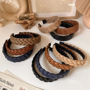 Assorted PU leather braided headbands in beige, brown, and navy blue stacked on a table