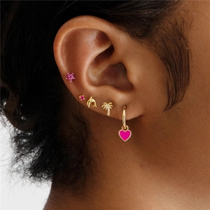 Detailed view of gold plated earrings set with pink flower, dolphin and heart pendants