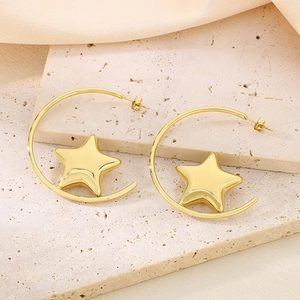 Detailed view of 18k gold C-shaped hoop earrings with star pendants on beige stone