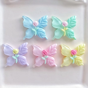 Macro detail of five macaron colored resin butterflies with mini rose decorations