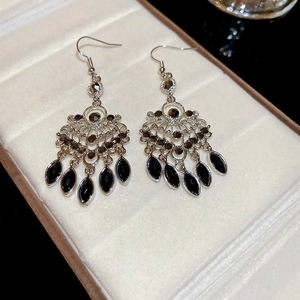Detail of vintage silver earrings featuring black rhinestones and teardrop pendants