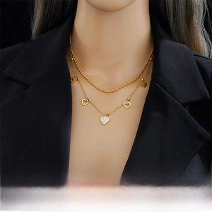 Double-layered gold heart pendant necklace with shimmering crystals on a model