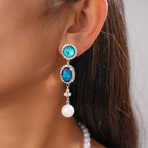 Detail of vintage drop earring with blue stones, pavé crystals and white pearl