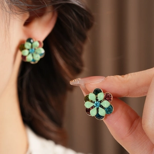 Detail of vintage flower earrings with blue crystal center and colorful enamel petals