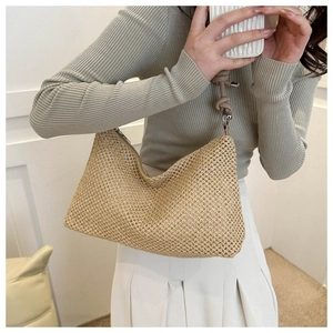 Detail showing handwoven texture and soft leather shoulder strap on a beige straw tote