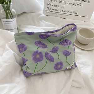 Trousse à maquillage en toile fleurie violette avec fermeture éclair sur lin blanc