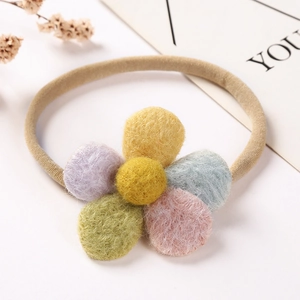 Détail d'un chouchou fleur en pompon coloré avec centre jaune et bande élastique souple