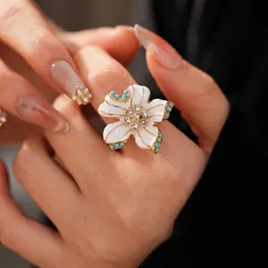 Bague fleur vintage en or avec émail crème et perles bleues sur la main d'un mannequin