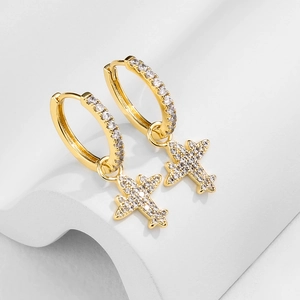 Close-up of gold cross earrings with zircon pavé on minimalist geometric background