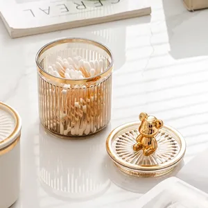 Luxury glass storage jar with a gold bear lid for cotton swabs on a marble surface