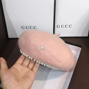 Detail of pink wool beret featuring pearl trim and silver metal letter M logo
