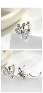 Close-up of elegant silver bow-knot earrings with pavé-set zircons and secure clasp