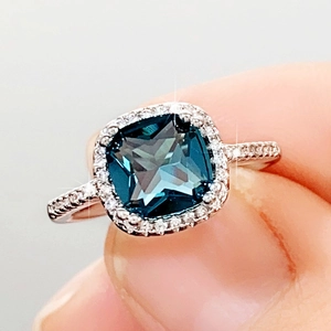 Classic cushion cut deep blue ring with halo diamonds on a polished silver band