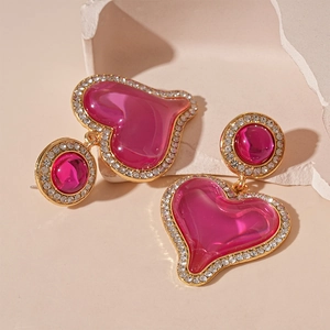 Exaggerated resin heart earrings with shimmering rhinestones and pink gold accents