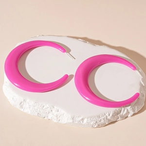 Macro shot of rose red acrylic C-shaped hoop earrings on a textured stone stand