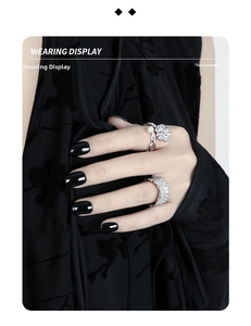 Detail of silver flower ring with pearl and textured band worn on hand with black nails